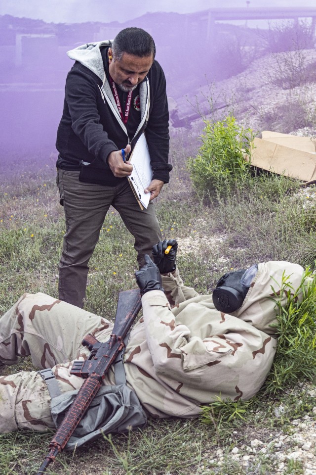A test officer oversees a Soldier wearing Mission Oriented Protective Posture (MOPP) gear test the Advanced Anticonvulsant System, Rafa Midazolam Auto-Injector (Rafa AI) at Camp Bullis, Texas on March 29, 2023. The test was organized by U.S. Army Medical Center of Excellence Medical Test and Evaluation Activity to conduct a human factors assessment of the effectiveness of the Rafa AI and if the device meets standards set by the Joint Program Executive Office - Chemical, Biological, Radiological, Nuclear Defense.