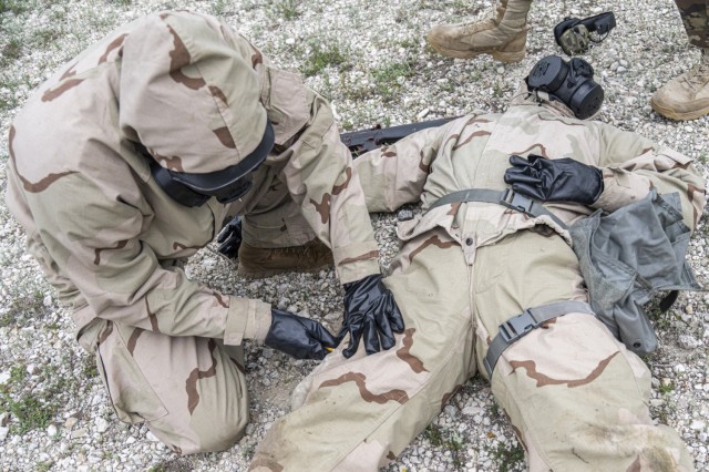 A Soldier wearing Mission Oriented Protective Posture (MOPP) gear prepares to test the Advanced Anticonvulsant System, Rafa Midazolam Auto-Injector (Rafa AI) on a fellow Soldier at Camp Bullis, Texas. The test was organized by U.S. Army Medical Center of Excellence Medical Test and Evaluation Activity to conduct a human factors assessment of the effectiveness of the Rafa AI and if the device meets standards set by the Joint Program Executive Office - Chemical, Biological, Radiological, Nuclear Defense.