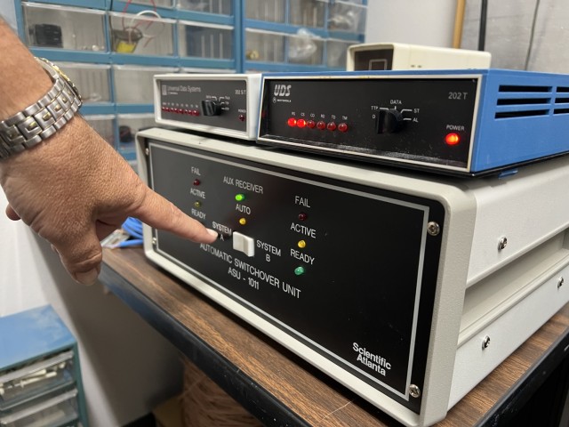 Kirk Farmer, manager of the Utility Monitoring and Control System, points to the FM-LMS and explains how the system uses radio frequencies to help reduce energy demand at Fort Cavazos facilities. (U.S. Army photo by Christine Luciano, DPW Environmental)