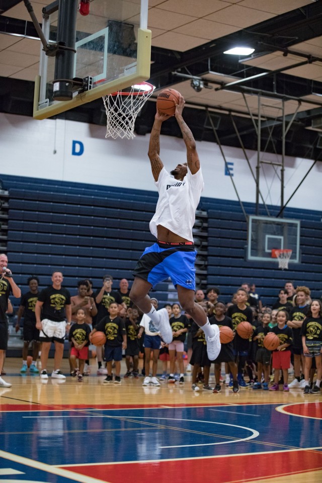 Marcus Smart attempts to dunk at the request of the children during the Marcus Smart Basketball Clinic June 24, 2023, on Fort Cavazos. "We care about (the children)," Smart said. "We care about their families. We're thankful for what their families are doing for our country."  (U.S. Army photo by Blair Dupre, Fort Cavazos Public Affairs)