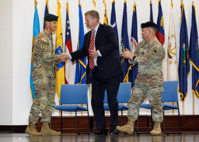 Col. Marcus S. Hunter, left, incoming commander of U.S. Army Garrison Japan, shakes hands with Craig Deatrick, director of U.S. Army Installation Management Command-Pacific, as Col. Christopher L. Tomlinson, the outgoing commander, watches on during a change-of-command ceremony at Camp Zama, Japan, July 7, 2023.