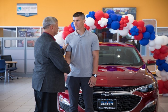 Ken Cox, vice president of AUSA Central Texas Chapter, presents Spc. Cameron Stout, 2nd Bn., 7th Cav. Regt., 3rd BCT, 1st Cav. Div., with a coin during a small ceremony June 28 at All American Chevrolet in Killeen.  (U.S. Army photo by Blair Dupre, Fort Cavazos Public Affairs)