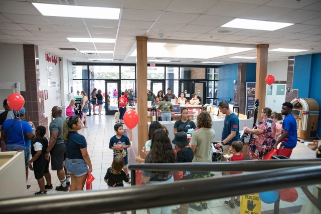 On Saturday, families form a line inside the lobby of the USO at Fort Cavazos Headquarters to collect their free backpack(s) as more families enter to participate in the Back to School Birthday Bash Event Aug. 5. The USO partnered with Freedom Mortgage and, through their Rucksacks to Backpacks Program, gave out 181 backpacks to Fort Cavazos youth. (U.S. Army photo by Blair Dupre, Fort Cavazos Public Affairs)
