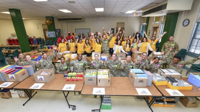 Teachers and staff of Briscoe Elementary School pose with Soldiers and civilians of the 187th Medical Battalion and members of the Royal Arch Masons in front of school supplies on Aug. 11, 2023. The battalion organized a school supply drive to help 315 students and families. 