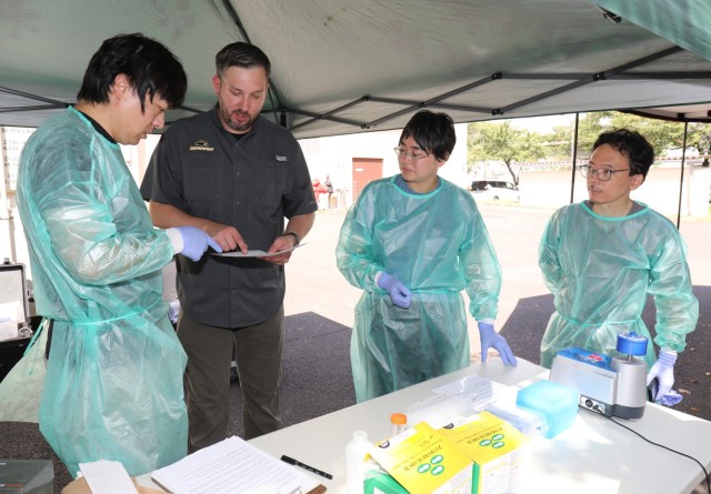 Dr. Gary Crispell, second from left, chief of Public Health Command–Pacific's Environmental Molecular Biology Laboratory, discusses how to perform pathogen analysis using a field lab as part of a knowledge-sharing event at Camp Zama, Japan, Aug. 21, 2023. Crispell and other PHC-P experts showed a handful of professors from the National Defense Medical College and interns in U.S. Army Garrison Japan’s summer internship program how to conduct the process in an austere setting.