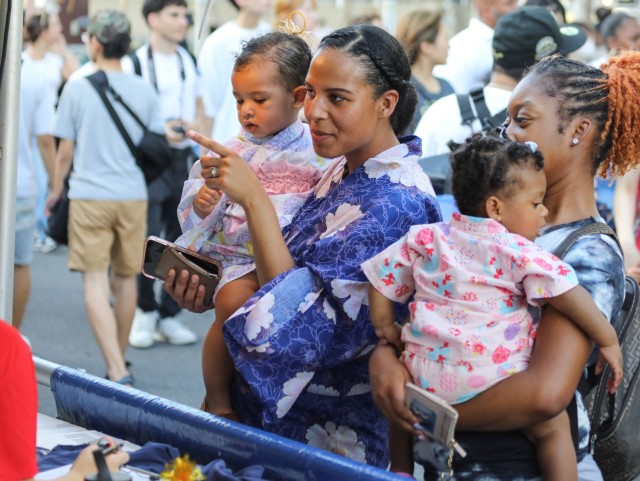 Spc. Alexis Washington, center, an information technology specialist for U.S. Army Japan’s G-6 office, and her friend, Princess Fortune, a military spouse, purchase balloons for their 1-year-old daughters, Sofia and Ivory, respectively, during the Bon Odori festival at Camp Zama, Japan, Aug. 5, 2023. 