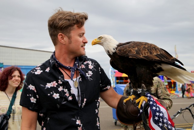 CAB Fest: A man holds a bald eagle in his left hand and admires it. 