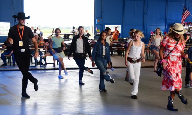 CAB Fest: A group of people are line dancing with an instructor next to them. 