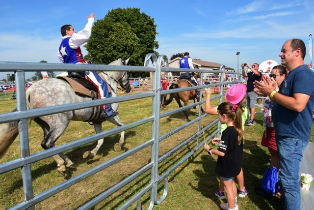 CAB Fest: Families watch horses behind a fence and cheer as they pass by. 