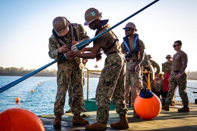 Seaman Boatswain's Mate Qwante Huggins, right, and Boatswain's Mate 3rd Class Joshua Banks, both assigned to Amphibious Construction Battalion 1, work together to affix the buoy connector aboard the commercial Australian vessel Bandicoot during Talisman Sabre 23 in Weipa, Australia, July 21, 2023. Huggins and Banks are part of the Joint Petroleum Over-the-Shore operation demonstrating critical logistical capabilities in the IndoPacific region. Talisman Sabre is the largest bilateral military exercise between Australia and the United States, with multinational participation, advancing a free and open Indo-Pacific by strengthening relationships and interoperability among key allies and enhancing our collective capabilities to respond to a wide array of potential security concerns.