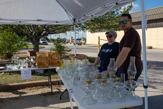 Stefanie Cole, Fort Cavazos Spouses Club Event Rentals, and her husband, Dan, smile toward a potential customer during the community yard sale Sept. 30. Cole sold items by donation on behalf of the FCSC, along with a few personal items. (U.S. Army photo by Samantha Harms, Fort Cavazos Public Affairs)