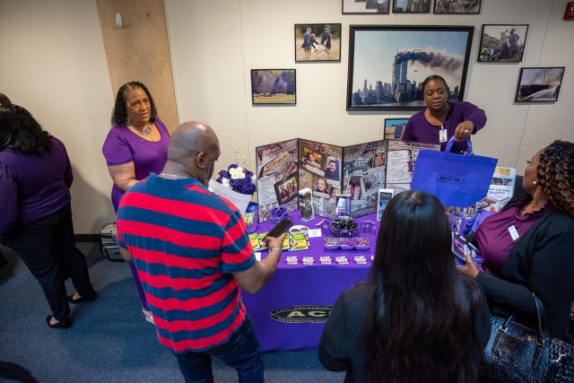 At the 2023 Domestic Violence Prevention Proclamation signing inside the III Armored Corps Headquarters’ East Atrium, a Family Advocacy Program educator engages attendees in conversation while they browse items on display at her table. (U.S. Army photo by Eric Franklin, Fort Cavazos Public Affairs)