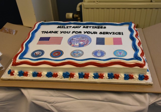 A cake with the words "Military Retirees Thank You For Your Service" and the U.S. and Belgian flag as well as crests from all military organizations. 