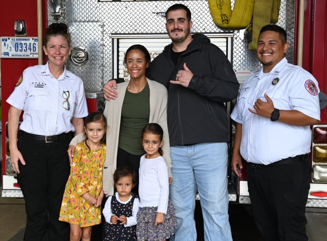 First responders from the Federal Fire Department, local EMS, and the Hawaii Fire Department gather, exemplifying the successful collaboration that saved Sergeant Dustin Charles Woodmansee's life. Key figures, including Mateo Mariano and Shalei Meneses, are pictured alongside Sgt. Woodmansee and his wife, Brittany. This powerful image captures the spirit of unity and dedicated service that defines their life-saving mission under mutual aid agreements.