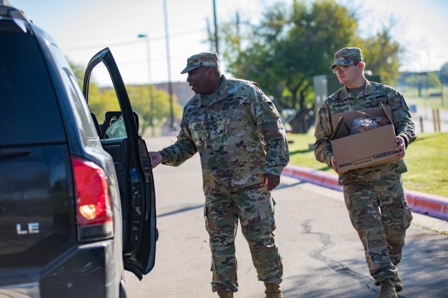 Command Sgt. Maj. Calvin Hall, U.S. Army Garrison-Fort Cavazos command sergeant major, and Spc. Bryce Popken, 2nd Battalion, 8th Cavalry Regiment, put a basket filled with fixings into a vehicle Nov. 15 during the giveaway. (U.S. Army photo by Blair Dupre, Fort Cavazos Public Affairs)