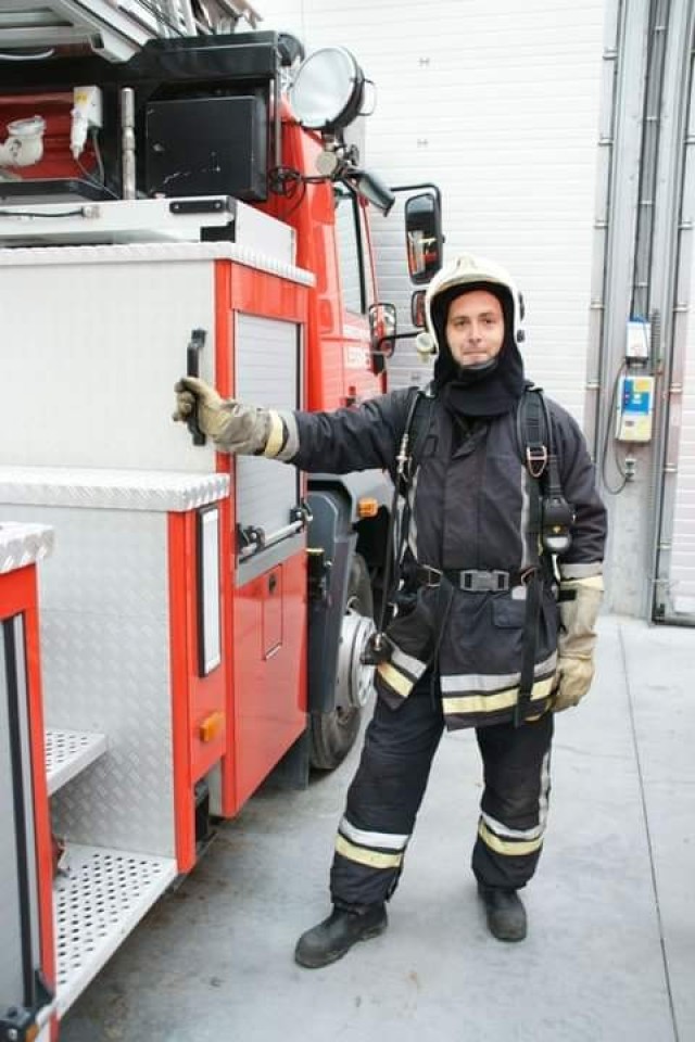 A Belgian firefighter stands next to a fire truck. 