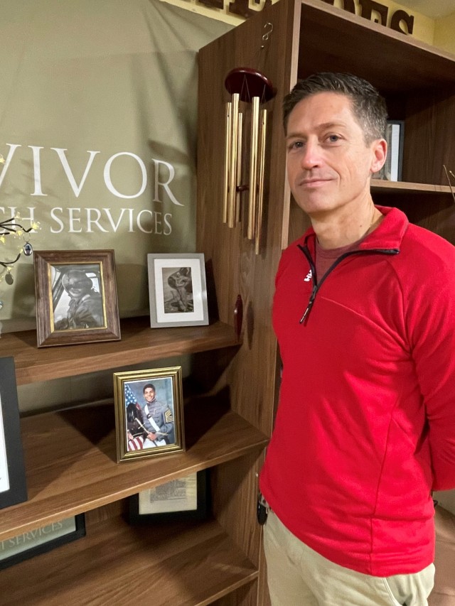 Luca Harbeson stands with a photo of his late father, Chief Warrant Officer 2 James R. Harbeson, who lost his life in a 1990 helicopter crash. The portrait of the late Harbeson is part of the Army Community Services Wall of Heroes. 