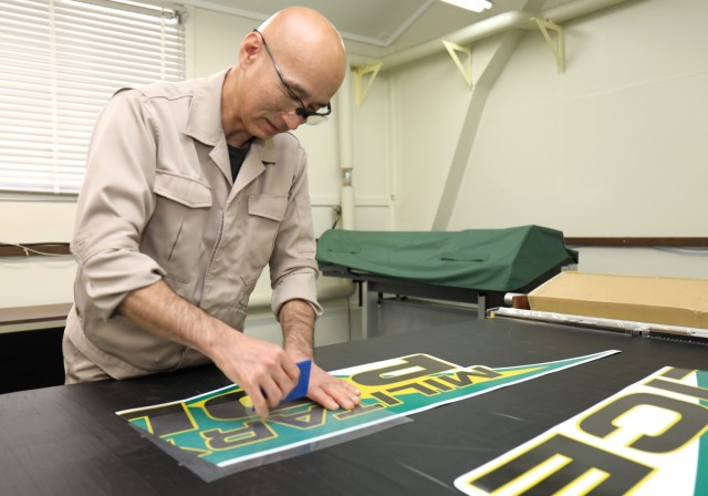 Takashi Yamamoto, an electronic mechanic with Logistics Readiness Center-Honshu, smooths over a decal for a new military police vehicle at Sagami General Depot, Japan, Feb. 7, 2024. U.S. Army Garrison Japan worked with partners to receive 12 patrol vehicles following a lengthy procurement process.