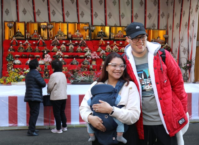 Spc. Jean Leon, right, a dental assistant for U.S. Army Dental Health Activity-Japan, and his wife, Joselyn Miranda pose for a photo with their son, Aaron, in front of a doll display in celebration of the Dolls Festival, or "Hinamatsuri," at the Zama Shrine in Japan, March 1, 2024. The Army Community Service at Camp Zama hosted a walking tour to the shrine for community members to enjoy the festival. 