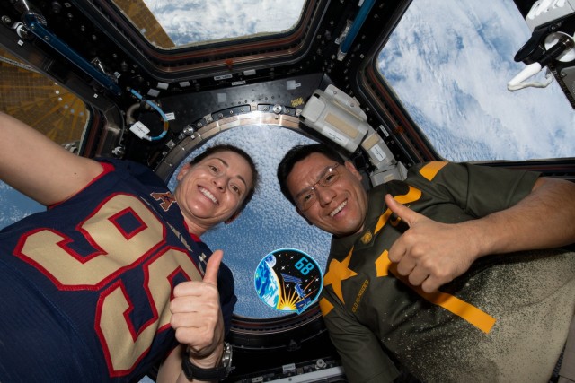 Expedition 68 Flight Engineers Nicole Mann and Frank Rubio, both from NASA, pose with their mission's insignia inside the cupola as the International Space Station orbited 262 miles above the northern Pacific Ocean, Dec. 10, 2022.