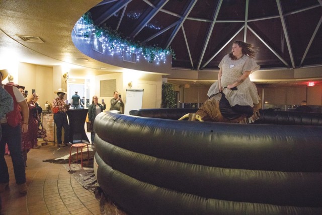 Wild West Night attendees brave the bucking mechanical bull during Wild West Night March 1 at the Lone Star Conference Center. There were also other western-themed activities, including casino games and line dancing. (U.S. Army photo by Blair Dupre, Fort Cavazos Public Affairs)