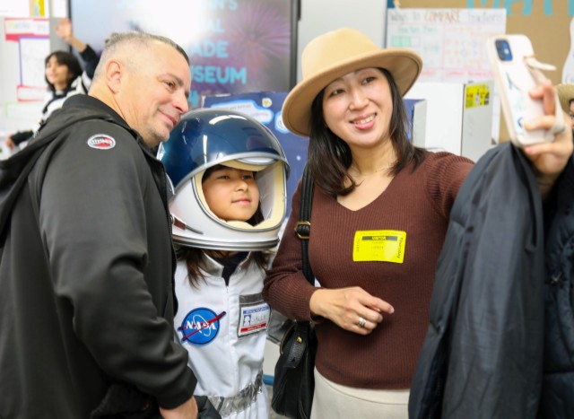 Anna Lisboa, center, poses for a photo with her parents, Nelson and Yukari, during a living wax museum event inside Arnn Elementary School at Sagamihara Family Housing Area, Japan, March 21, 2024. Anna, a fourth grader, portrayed astronaut Sally Ride for the museum, the culminating event of a school project that began in the fall.