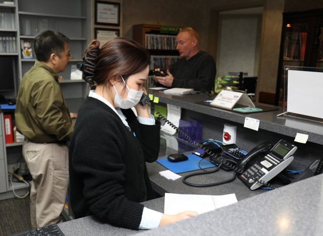 Mai Nemoto, a front desk clerk at the Camp Zama Army Lodging in Japan, and Mark Akita, left, lodging manager, help customers inside the facility March 5, 2024. The lodging team recently won the fiscal 2023 Lodging Operation of the Year Award for medium-sized facilities.