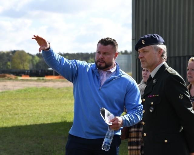 Two men in discussion about future land construction with their focus off camera towards a field. 