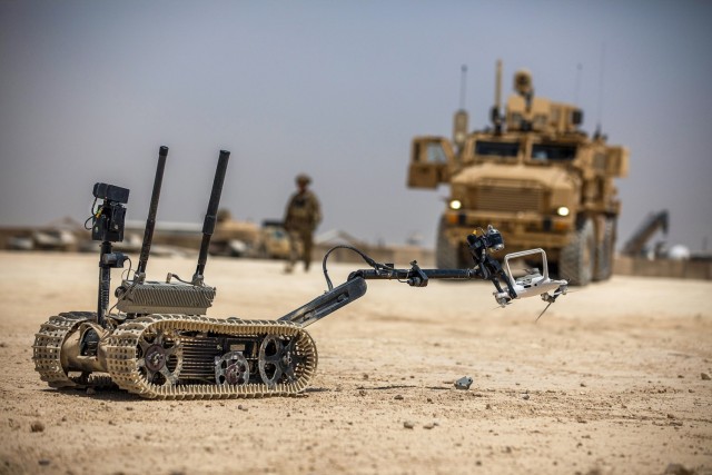 A TALON tracked military robot picks up a downed unmanned aerial system at Al Asad Air Base, Iraq, May 19, 2020. 