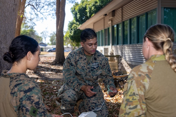 U.S. Navy Petty Officer 2nd Class Abm Asim, center, a hospital corpsman with Marine Rotational Force – Darwin 24.3, demonstrates how to prepare equipment to draw blood to Petty Officer 3rd Class Ariana Buckley, left, a hospital corpsman with Combat Logistics Battalion 5 (Reinforced), MRF-D 24.3, and Australian Army PTE. Melissa Murray, a medical technician with 1st Health Battalion, 2nd Health Brigade, during Valkyrie emergency fresh whole blood transfusion training at Robertson Barracks, Darwin, NT, Australia, May 16, 2024. The Valkyrie program enables military units to self-supply blood through emergency donor panels by adequate training, rehearsal, and preparation, gaining the skills and knowledge to efficiently collect whole blood, and conduct blood transfusions in the event of a casualty. Asim is a native of Florida. Buckley is a native of New York. (U.S. Marine Corps photo by Cpl. Juan Torres)