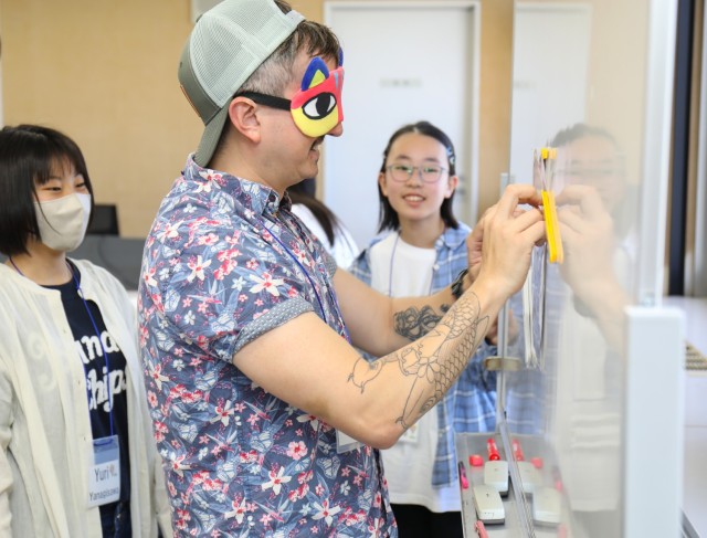 Spc. Felix Trujillo III, assigned to U.S. Army Medical Department Activity-Japan, plays the "fukuwarai" game with Japanese students during a language and cultural event at Zama City Hall, Japan, May 3, 2024. The volunteers helped a group of students get ready for an exchange trip this summer to Zama City’s sister city in Tennessee.