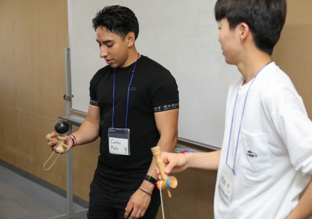Spc. Carlos Melo, left, assigned to the 38th Air Defense Artillery Brigade, practices the kendama game with a Japanese student during a language and cultural event at Zama City Hall, Japan, May 3, 2024. The volunteers helped a group of students get ready for an exchange trip this summer to Zama City’s sister city in Tennessee.