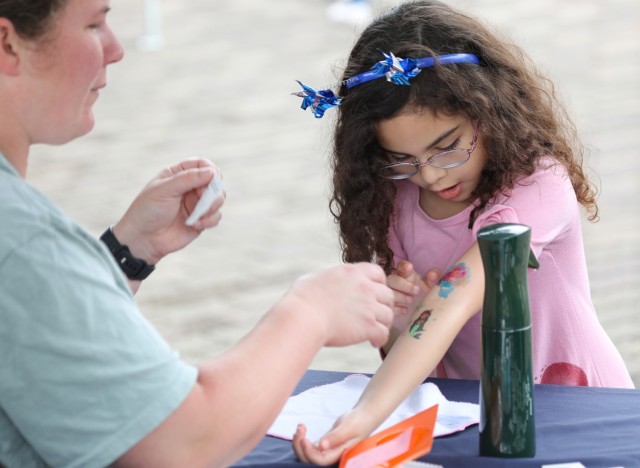 Emma Rosales, right, receives a temporary tattoo during a pinwheel planting event in support of National Child Abuse Prevention Month at Sagamihara Family Housing Area, Japan, April 30, 2024. The event had several activities for children including arts and crafts and games. 