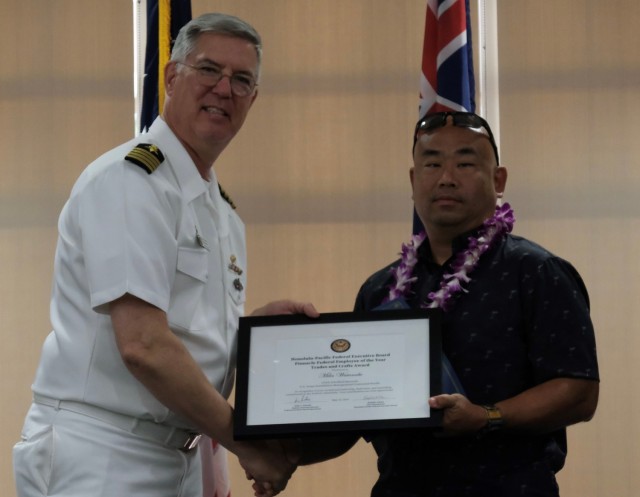 Miles Watanabe, Air Conditioning Equipment Mechanic Leader, U.S. Army Garrison Hawaii (right) accepts the Pinnacle Award as the best in the Federal Employee of the Year – Trades and Crafts category from Capt. Richard Jones, Commander, PHNSY & IMF at the Honolulu-Pacific Federal Executive Board’s Annual Excellence in Federal Government Awards ceremony at the Tradewinds facility on Joint Base Pearl Harbor Hickam, Hawaii on May 10.  