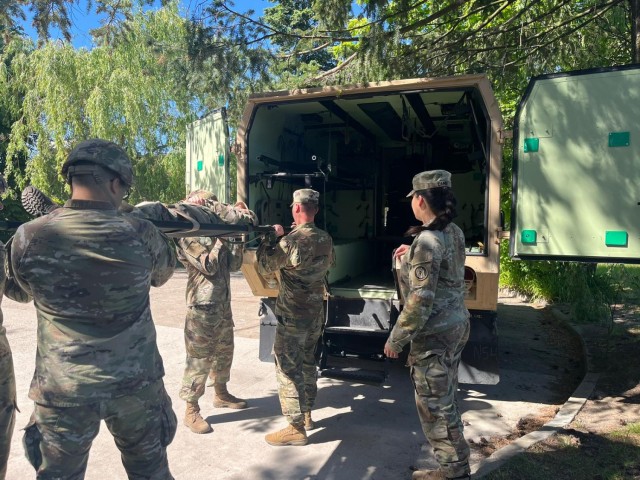 1st Lt. Isabella Carr guides evacuation soldiers on loading a patient safely into the field litter ambulance.