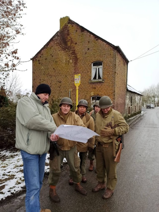 A man shows U.S. Soldiers a map of WWII battle sites.