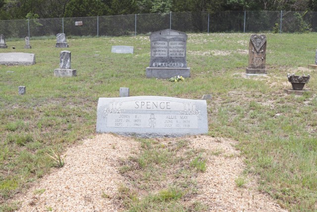Stone headstones of various shapes and sizes sit in rows over a large area of grass. 