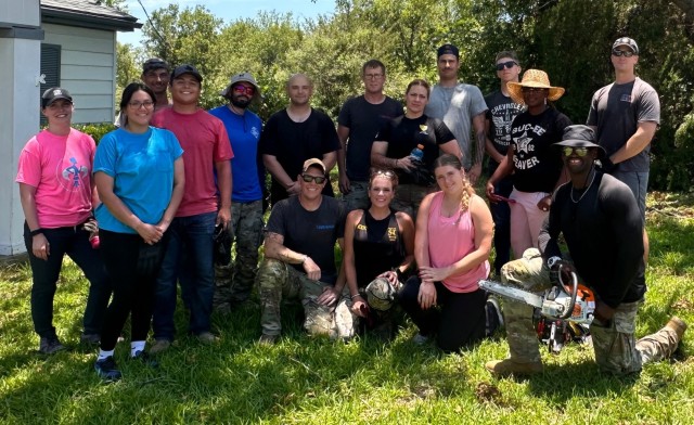 A group of people pose for a photo outside on grass. 