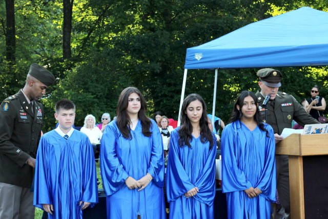 Lt. Col. Craig A. Bonham II, Picatinny Arsenal Garrison Commander (on left) and Command Sgt. Maj. David M. Franks (right), recognize Byram Intermediate School students Connor Eastman, Gabrielle Landie, Angeline Lavrador, and Brianna Mesias for their participation in the wreath laying ceremony at the Tomb of the Unknown Soldier at Arlington National Cemetery in Arlington, Virginia.  The students received certificates of appreciation and military challenge coins at their eight-grade graduation on June 17.