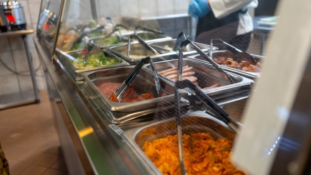 Behind glass, pans of various food ingredient sit in rows, with tongs in each pan.
