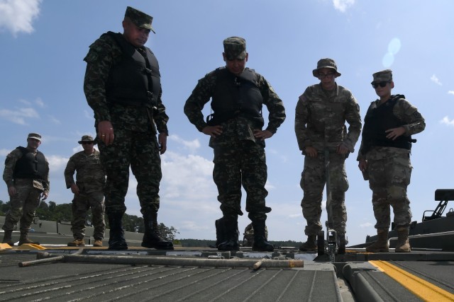 U.S. Army Pfc. Micah Grover, a bridge crewmember with the 125th Multi-role Bridge Company, South Carolina Army National Guard, locks together two floating bridge sections as Lt. Col. Jorge Flechas, left, and Maj. Jhon Chaparro, both with the...