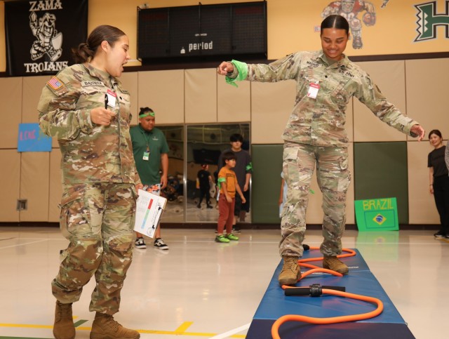 Spc. Nayci Madrid, right, a member of the Better Opportunities for Single Soldiers program, balances herself in the high beam contest during a mini-Olympics event at the Youth Center at Camp Zama, Japan, July 24, 2024. The event had six sporting...