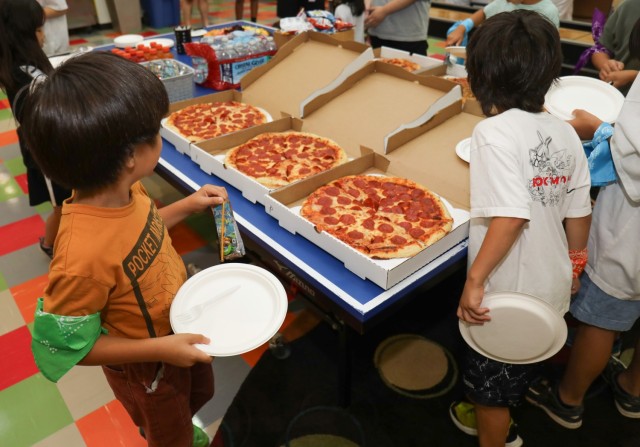 Sagamihara Minami Children’s Home residents enjoy a snack break with pizza, fruit and a cake with the Olympic rings on it during a mini-Olympics event at the Youth Center at Camp Zama, Japan, July 24, 2024. The event had six sporting activities...