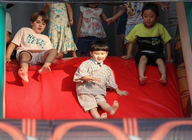A group of children slide down an inflatable bounce castle during an Independence Day celebration at Camp Zama, Japan, June 29, 2024. More than 16,000 people attended the daylong event that had plenty of food and entertainment including...