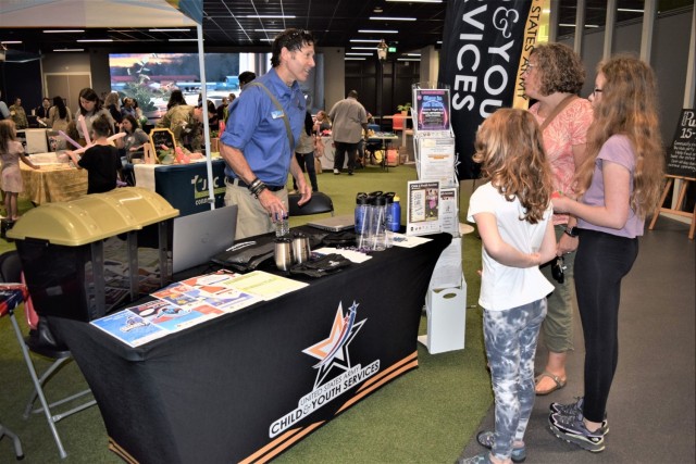 CYS employee stands at table and gives information to newcomers