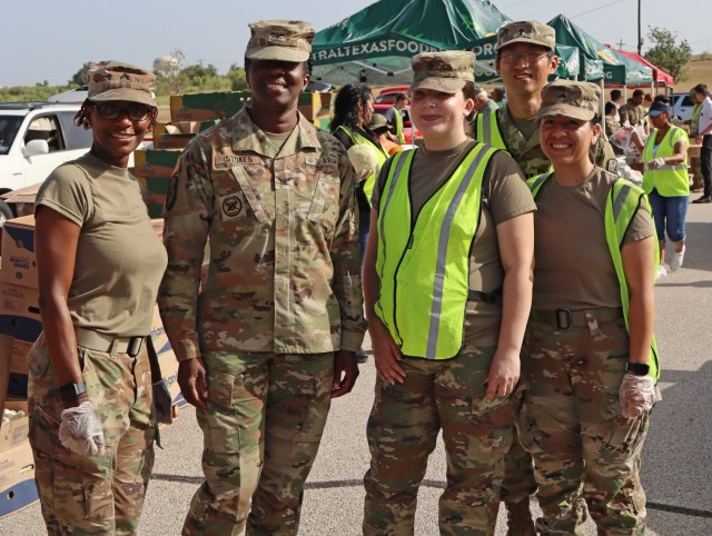Five people, all in operational combat pattern uniforms pose for a picture standing.