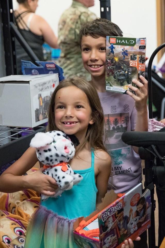 Two children holding toys while standing pose for a picture.
