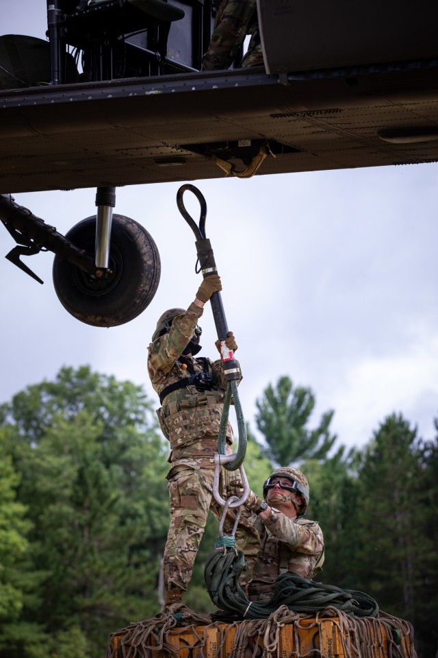 Oklahoma Army National Guard Spc. Michael Champion, a combat medic assigned to headquarters battery, 1st Battalion, 160th Field Artillery Regiment, 45th Infantry Brigade Combat Team, hooks a cargo load of ammo to a UH-60 Black Hawk during...