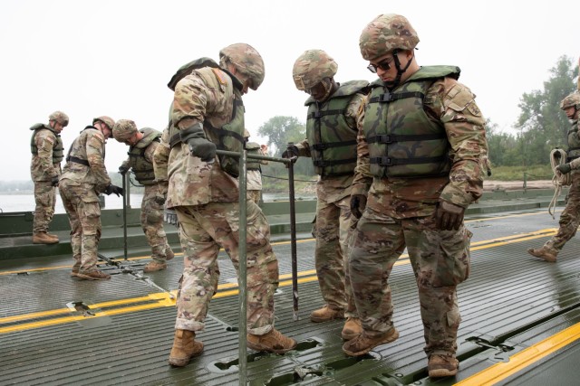 Soldiers with the 957th Multi-role Bridge Company, North Dakota Army National Guard, use T-bars to secure two floating bays of an Improved Ribbon Bridge during a wet gap crossing training exercise on the Missouri River near Kimball Bottoms, North...