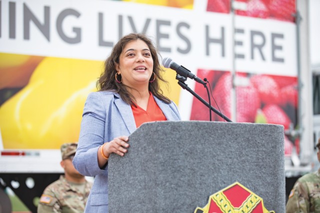 A woman standing speaks behind a podium.